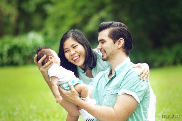 Happy Mixed Race Family Playing with New Born Baby at Park