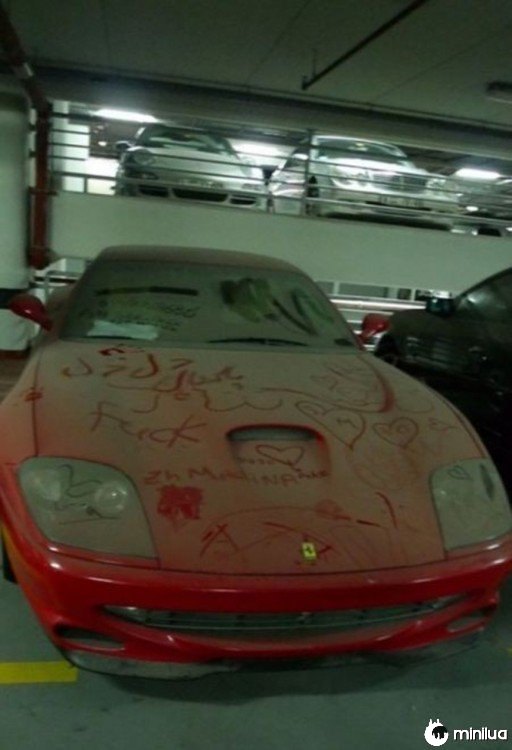 Ferrari vermelho cheio de poeira em um estacionamento em Dubai 